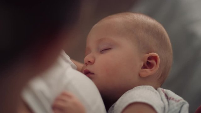 Mother slowly rocks sleeping baby boy in her arms, filmed with red helium 8K