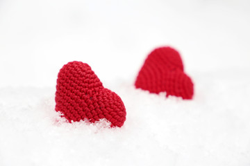 Valentines hearts, greeting card, two red knitted symbols of love in the snow. Background for romantic event, celebration or winter weather