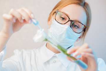 Scientist extracts oil syringe from flowers test natural cosmetics extract aroma. Buds leaf in glass flask. Biotechnology concept