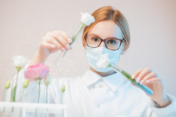 Natural cosmetics flower extract, oil from plants and leaves. Biotechnologist doctor in white uniform holds flags in hands