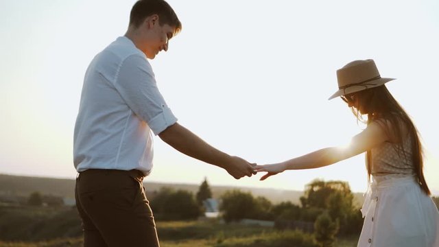 Happy couple at the sunset in rural landscape. Young millennials couple, romantic scene. Family life and having fun together