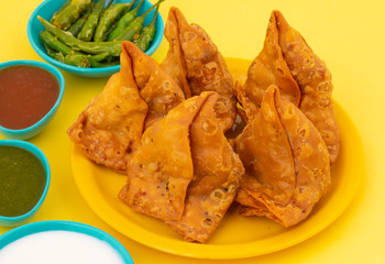 Indian Street Food Samosa or Samosas is a Crispy And Spicy Triangle Shape Snack Which Has Crisp Outer Layer of Maida & Filling of Mashed Potato, Peas And Spices. Served With Chutney, Ketchup or Curd
