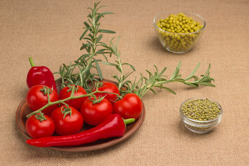Diet  food concept. Tomatoes, green peas, lentils, chili peppers and a sprig of rosemary on burlap.