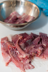 Sliced meat from carp on table and metal bowl in background.