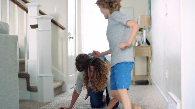 Mid 30s mother plays with her sons, giving a piggy back ride and teasing 4K