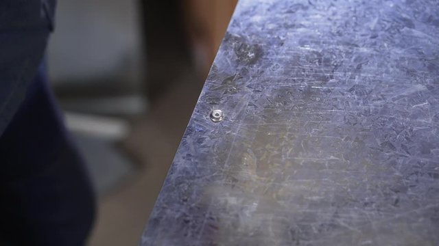 Rivet pistol in action. Factory worker installing rivets on metal surface with rivet pistol. Worker in metalworking plant attaching metal parts with tool