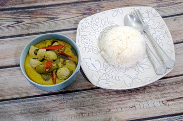 Green curry with fish balls and steamed rice on a wooden table