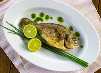 Plate with grilled dorado fish and sliced lime.