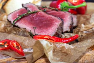 fresh grilled beef meat rib eye steak on kraft paper with baked tomatoes, garlic, hot chili and rosemary