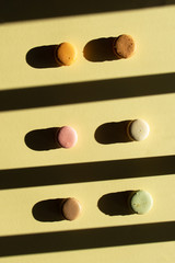 Contemporary flat lay composition pastel macaron on light yelow backgraund with dark shadow.
