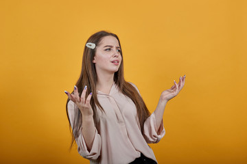 Disappointed caucasian brunette woman in fashion pastel shirt staying sideways, spreads hands,...