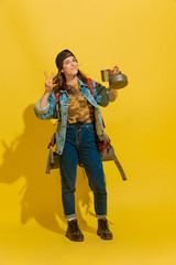 Fototapeta na wymiar Tea time on nature. Portrait of a cheerful young caucasian tourist girl with bag and cups isolated on yellow studio background. Preparing for traveling. Resort, human emotions, vacation. Happy