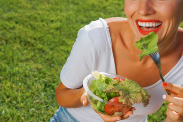 Beautiful caucasian woman eating salad over green natural background