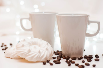 Meringue with coffee. two cups, white background with bokeh.