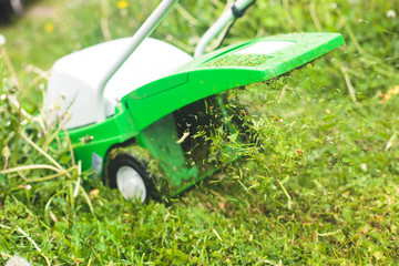 A process of lawn mowing, concept of mowing the lawn, lawnmower cutting grass with gardening tools and green grass around