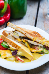 Classic breakfast, hot sandwiches with cheese, vegetables and chicken on a wooden table.