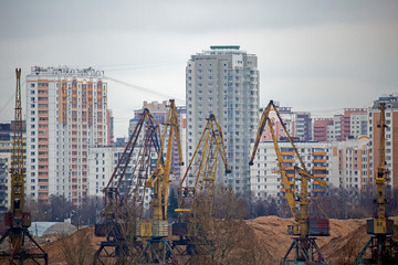 Industrial cranes on a background of high-rise buildings. Modern industrial urban concept