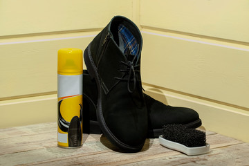 suede leather shoes stand on the podium, next to a bottle of water-repellent spray and a cleaning...