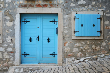 Blue window  with wooden shutter and door with handle in vintage style in house made from stone. Acient architecture building.