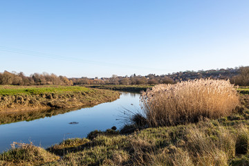 Looking along the River Ouse in Sussex on a sunny winters day, with the town of Lewes in the distance