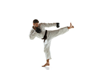 Confident coach in kimono practicing hand-to-hand combat, martial arts. Young male caucasian fighter with black belt training on white studio background. Concept of healthy lifestyle, sport, action.