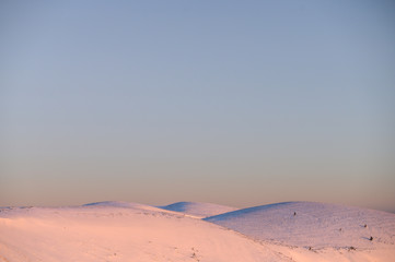Fototapeta na wymiar Hills in winter on the bottom of image, white edit space