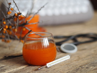 Sea buckthorn jam, tea, lemon for the treatment of influenza. Warm clothes, a thermometer, a medical tool and an appicator. Sprig of dry sea buckthorn on a wooden ancient background.