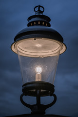 Old outdoor lamp in the evening against a very dark and cloudy sky