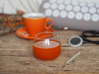Sea buckthorn jam, tea, lemon for the treatment of influenza. Warm clothes, a thermometer, a medical tool and an appicator. Sprig of dry sea buckthorn on a wooden ancient background.