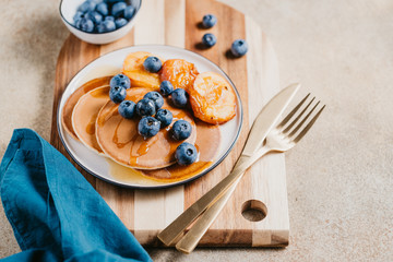 Close up of pancakes with grilled peaches, fresh blueberry and maple syrup.