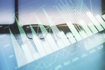 Financial graph hologram with glasses on the table background. Concept of business. Double exposure.