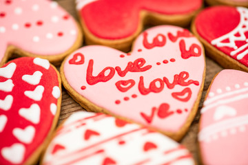Gingerbread hearts festive on Valentine's Day on a wooden background. Delicious and sweet, covered with icing with a beautiful pattern, handmade. The view from the top.  Macro.