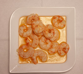 peeled shrimp in sauce on a white plate
