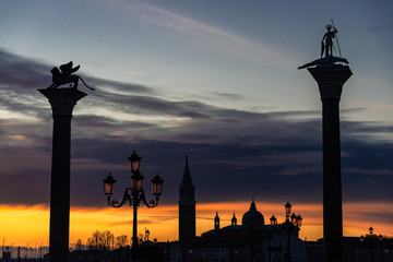 Fototapeta na wymiar Breathtaking sunrise view of empty San Marco square in Venice on orange sky and San Giorgio Maggiore silhouette background