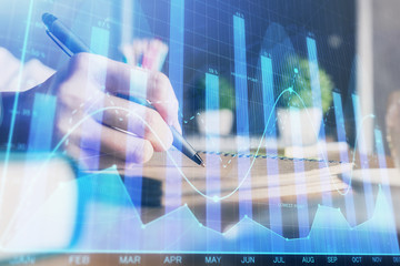 Financial forex charts displayed on woman's hand taking notes background. Concept of research. Double exposure