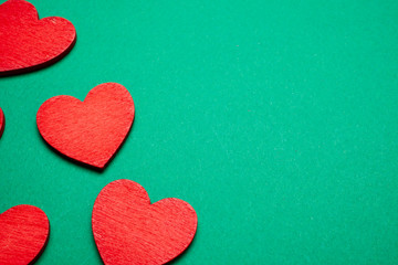 Fototapeta premium Red decorative hearts over green background. Valentine's Day, love celebration. Copy space. Top view.