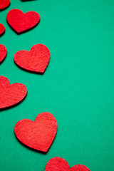 Red decorative hearts over green background. Valentine's Day, love celebration. Copy space. Top view.