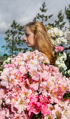 Naklejka premium young woman among the flowers of azalea