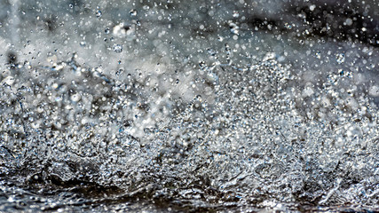 Naklejka na ściany i meble Water splash with small drops in the fountain. Abstract natural, selective focus background
