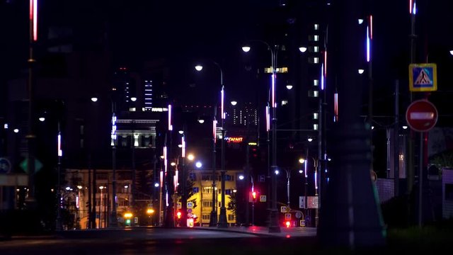 Night landscape of the big city center with shining lights and moving rare cars. Stock footage. Road of the central city district lit by street lamps.
