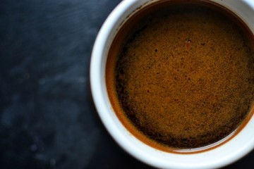 Natural coffee in a white cup. Coffee top view. Coffee with cream on a dark, dark blue background. Place for text.