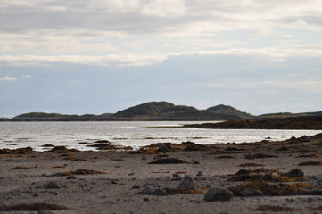 View to the sea and Vega archipelago mountains from the foot of the mountain Torghatten in Torget island in Brønnøy Municipality in Nordland county, Norway on sunny summer evening