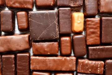Assortment of chocolates. Candies on a dark bluish background. Top view place for text. Dark chocolate. Chocolate bars.