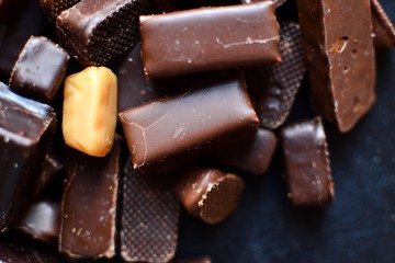 Assortment of chocolates. Candies on a dark bluish background. Top view place for text. Dark chocolate. Chocolate bars.