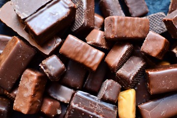 Assortment of chocolates. Candies on a dark bluish background. Top view place for text. Dark chocolate. Chocolate bars.