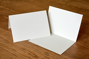 Closed and open blank empty greeting card mock up on dark wooden background. For use as a Christmas, birthday, wedding or celebration background template.    