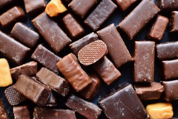 Assortment of chocolates. Candies on a dark bluish background. Top view place for text. Dark chocolate. Chocolate bars.