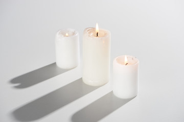 Fototapeta na wymiar burning candles glowing on white background with shadow