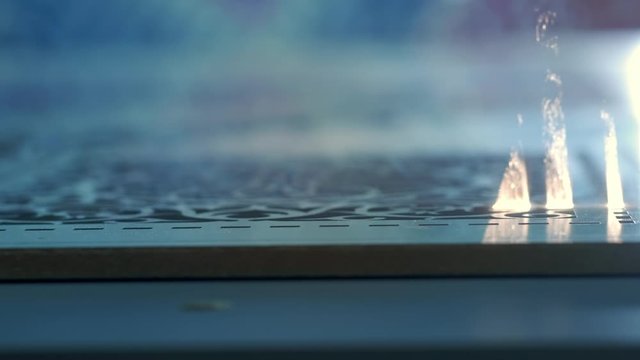 Industrial Laser cutting on wood, cutting a pattern on a plywood sheet and moving slowly, close up. A large technological machine burns through a wooden board. New technologies in woodworking.