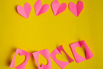 Red paper hearts on yellow background. Valentine's Day concept.